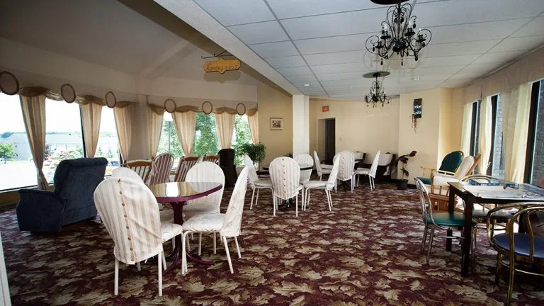 The bright Rendez-vous hall with chandeliers, tables and seating arranged for a gathering