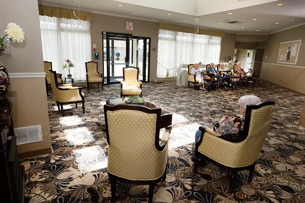 The sunlit main lounge with elegant armchairs where residents gather and visit