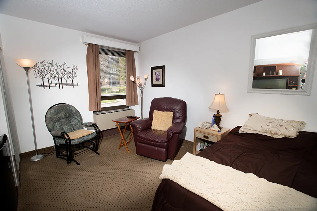 The Room with Village View — bed, glider chair, leather armchair and a window onto the village